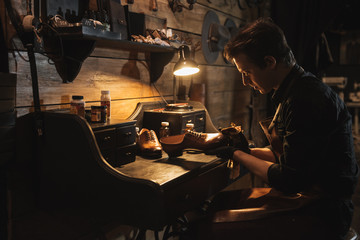 Naklejka premium Concentrated man shoemaker at footwear workshop.