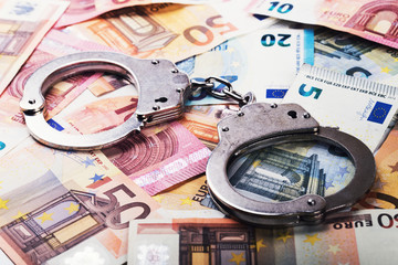 tax evasion, corruption concept - handcuffs on euro money bills