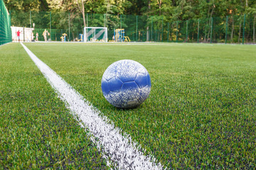 The ball lies near the lateral line of the soccer field with artificial turf close-up. © Maksym S