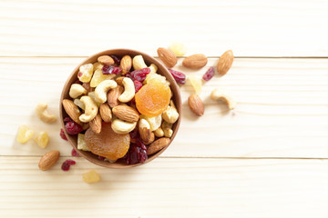 mixed nuts and dried fruit in wooden bowl on wooden table top view. Walnut, pistachio, almond, hazelnut, cashews, apricot, berry, banana, pineapple, Healthy food and snack