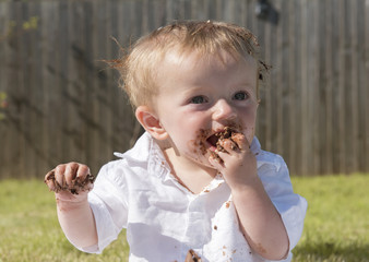One year old baby boy eating chocolate cake 