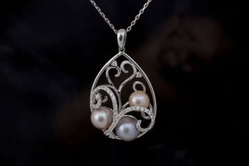 Pearl, diamond white gold necklace on black background