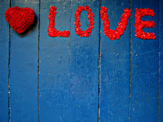 The word "love" with crystals of salt on a cherry blue boards and knitted heart next.