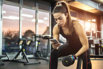 Fototapeta na wymiar Young woman using phone at gym.