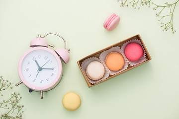 French macaroons. Many variegated sweet macarons in box with bouquet of pink roses on the table