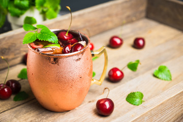 Cherry moscow mule on the wooden background. Selective focus.