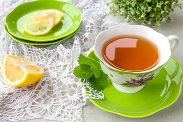 Tea in a cup of green and a bud of clematis colors in a rural style on a light background with a copy space