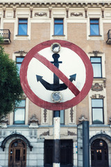Sign for ships the anchor crossed red line. Warning sign prohibiting ships mooring riverside on background of building