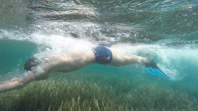 Swimmer in flippers dives into the sea, raw, 4K