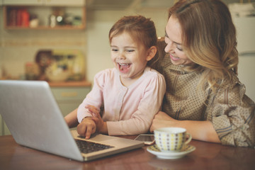 Mother with daughter using laptop.