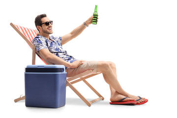 Tourist sitting in a deck chair and toasting with beer
