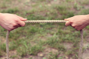 one second before the confrontation/ two hands holding a thick rope on different sides 