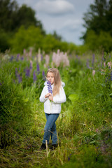 Fototapeta premium Girl with a bouquet in the hands of purple flowers lupine field Purple flowers lupine field sunset