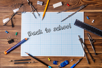 Graph paper with text - back to school and student material on wooden table.