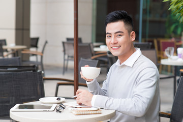 Fototapeta na wymiar Handsome young man drinking coffee at city