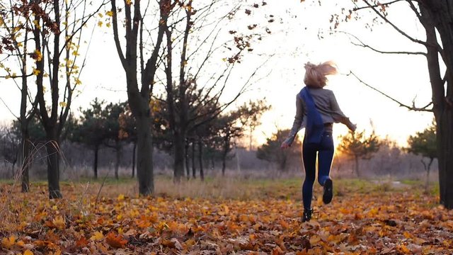 Young girl happiness hidden among the autumn colorful leaves in sunset