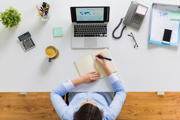businesswoman writing to notebook at office