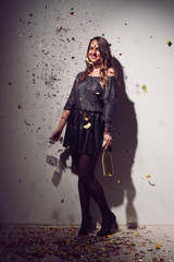 Woman posign. Home party. Lot of confetti around her.