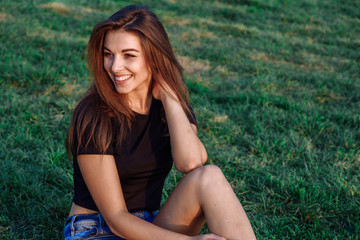 Naklejka na ściany i meble Summer spring portrait of young beautiful woman smile in the park sunset
