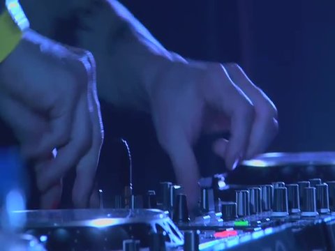 HANDS OF A DJ TOUCHING THE MIXTURE DURING AN ACT IN A CLUB