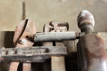 Close up of old used rusty tools on wooden table against brown grey wall