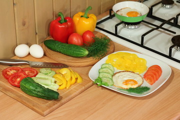 Scrambled eggs on a white plate with fresh vegetables and herbs.