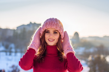 Winter portrait of a Happy candid beautiful young lady in a pink knitted beanie hat and gloves