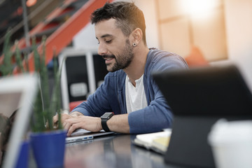 Fototapeta premium Man working in coworking office on laptop