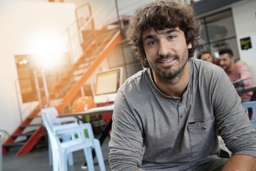 Portrait of cheerful guy sitting in loft office