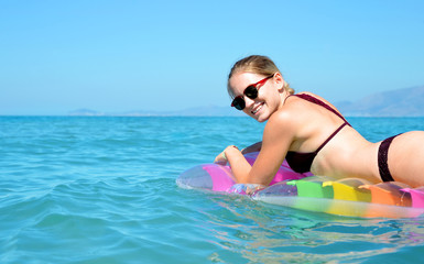 Young girl floating on inflatable mattress in the sea. Summer vacation.