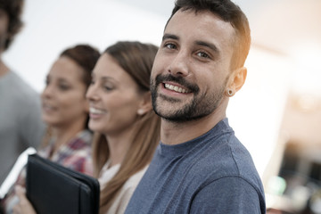 Obraz premium Portrait of cheerful guy in office with workmates