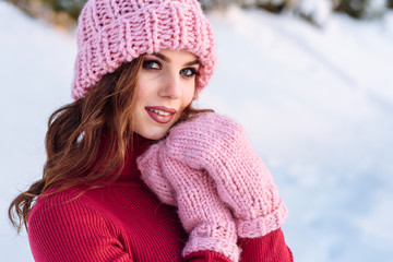 close up Winter portrait of a Happy candid beautiful young lady in a pink knitted beanie hat and gloves