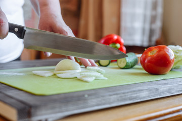 Female hands cutting bulb onion, on kitchen background