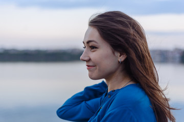 Summer happy portrait beautiful woman girl caucasian asian blended in blue shirt posing on background sky lake water sunset long hair brunette outdoors