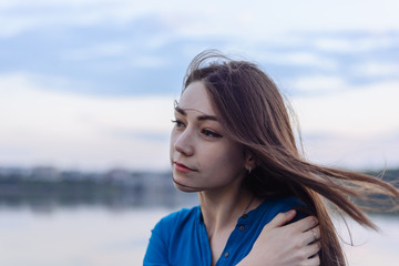 Summer happy portrait beautiful woman girl caucasian asian blended in blue shirt posing on background sky lake water sunset long hair brunette outdoors