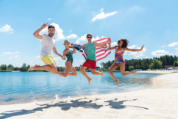 Jolly youthful friends enjoying their rest on river shore