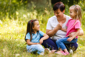 Picture of young mother hugging two little children, closeup portrait of happy family, cute brunette female with daughter and son outdoor in spring time, smiling faces, happiness and love concept