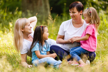 Fototapeta premium Two mothers with their children outdoor in summer park