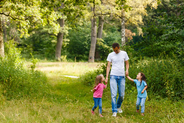Fototapeta premium father enjoying spring walk with two smiling kid daughters. Family with two sisters happy together