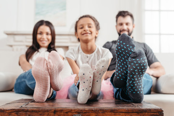 happy multicultural family in colorful socks sitting on sofa together