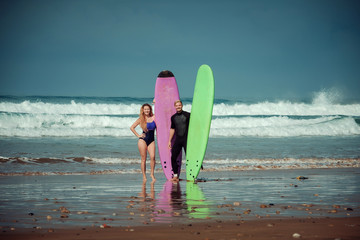 Surfer couple on the beach with a surfing board