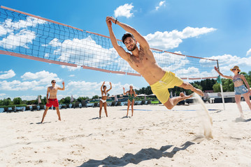 Cheery youthful guys spending actively spare time on river beach