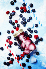 Iced fruit tea with forest berry and ice in glass bottle, top view