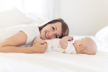 Portrait of mother with her 3 month old baby in bedroom