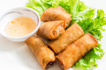 Deep fried spring rolls and sweet sauce on white plate.