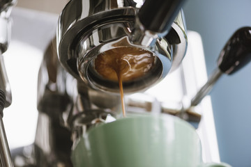 The process of making coffee step by step. Delicious freshly ground morning espresso coffee with a beautiful crema pouring through the bottomless (naked) portafilter into a ceramic green cup