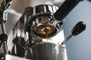 The process of making coffee step by step. Delicious freshly ground morning espresso coffee with a beautiful crema pouring through the bottomless (naked) portafilter into a grey cup. Horizontal photo