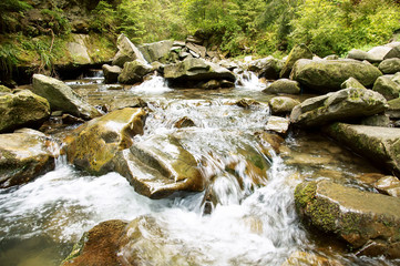 Naklejka na ściany i meble Large stones on a mountain river with clear blue water.Carpathians