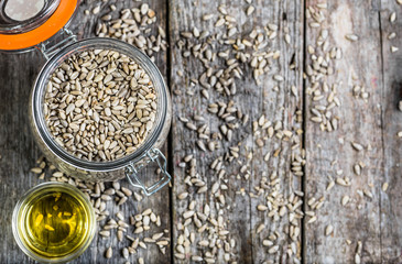 Sunflower oil and sunflower seeds in jar on wooden table