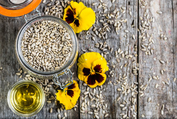 Sunflower oil and sunflower seeds in jar on wooden table